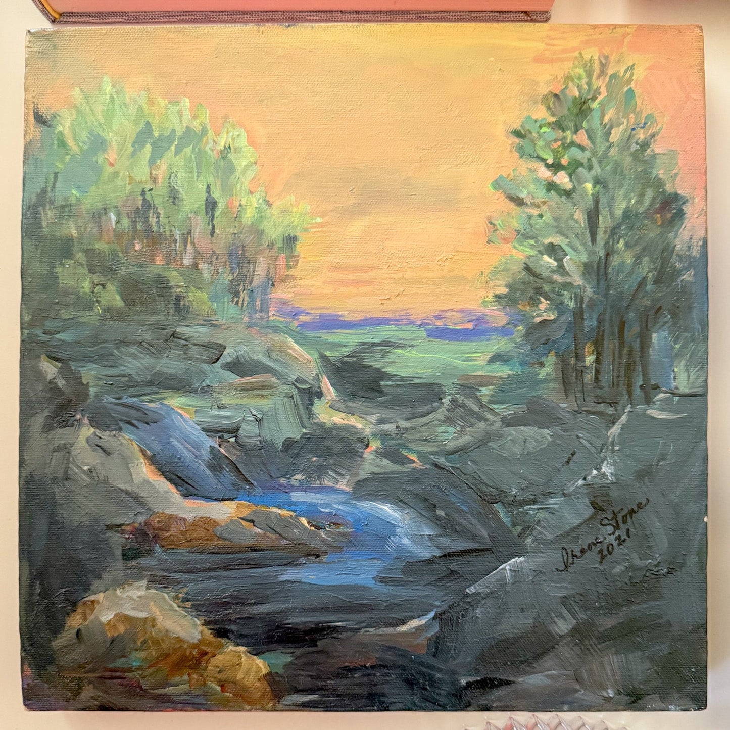 Painting of a landscape with trees and a river on a wall.