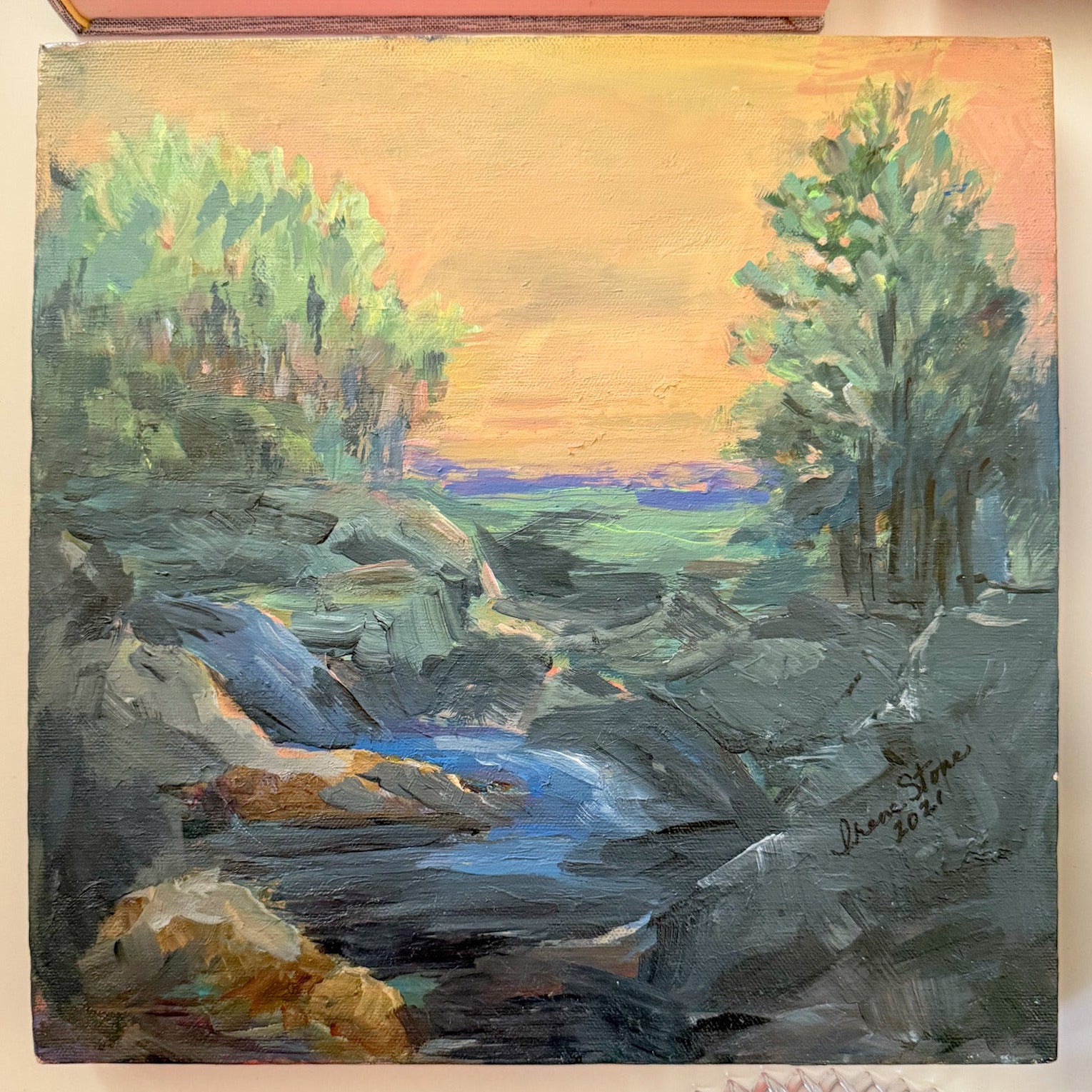 Painting of a landscape with trees and a river on a wall.