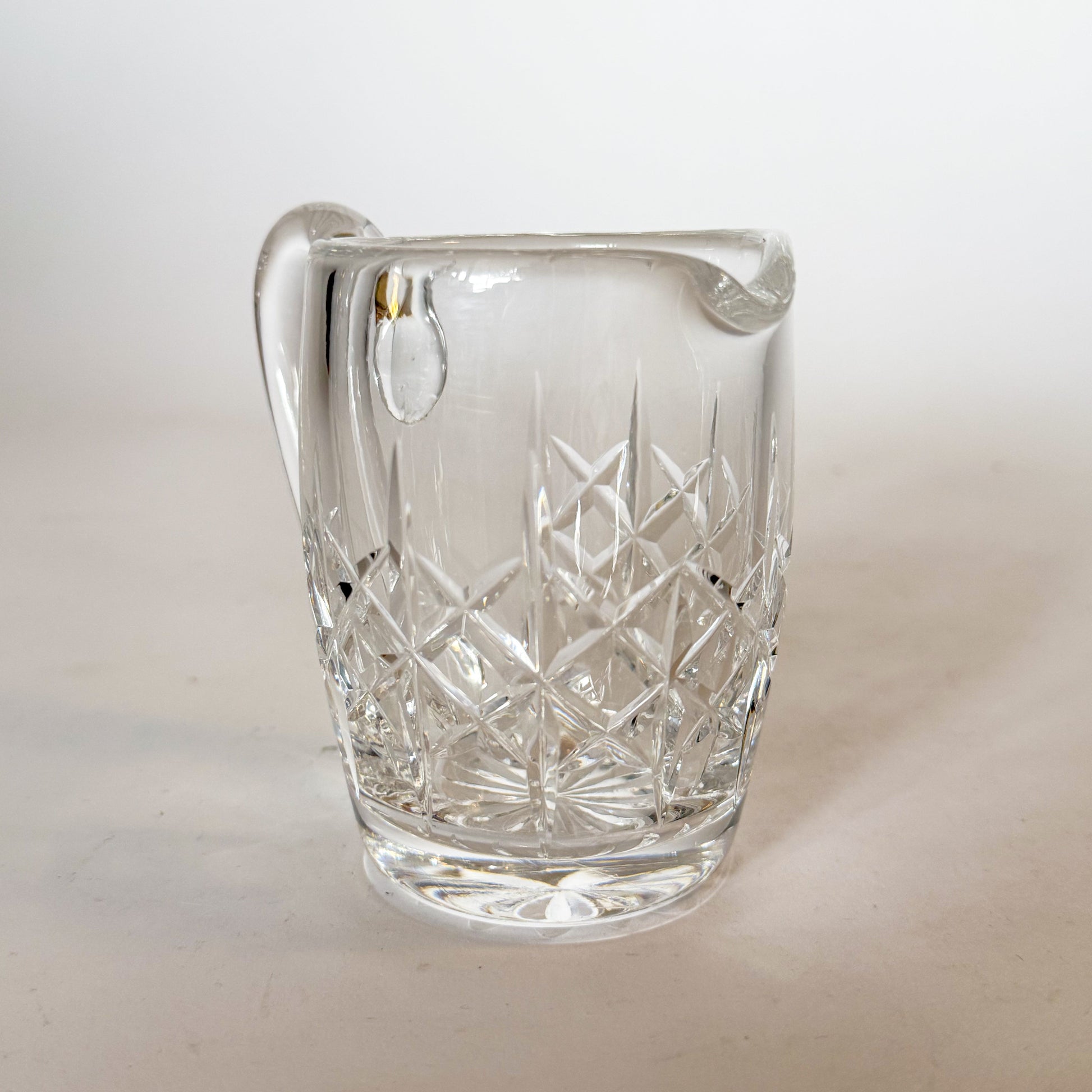 Clear glass pitcher with diamond pattern on a white background